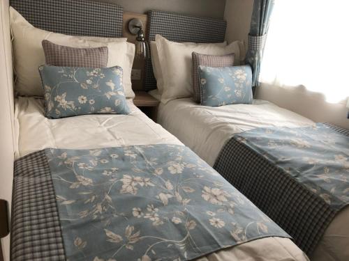 Luxury 2 bedroom caravan in stunning location في بيتلوكري: سريرين يجلسون بجانب بعض في غرفة النوم