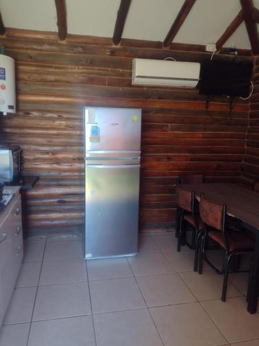 a refrigerator in a kitchen with a table and chairs at CABAÑAS EL CERRO in Ciudad Lujan de Cuyo