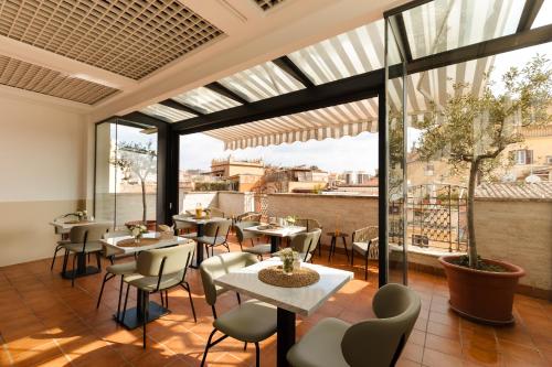 a restaurant with tables and chairs and large windows at Sonder Piazza di Spagna in Rome