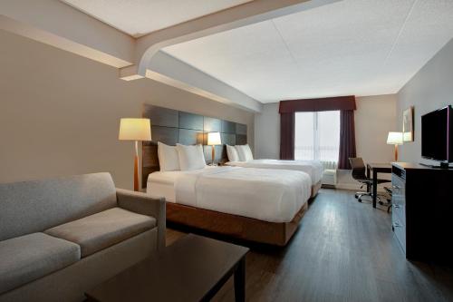 a hotel room with a bed and a couch at Days Inn & Suites by Wyndham Collingwood in Collingwood