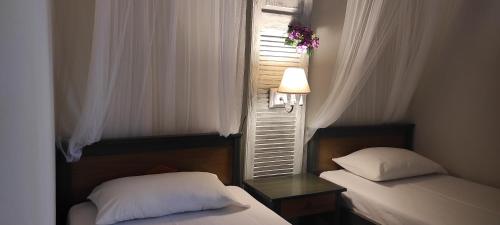 マクリ・ギアロスにあるNiki Apartmentsのベッドルーム1室(ベッド2台付)、花の咲く窓が備わります。
