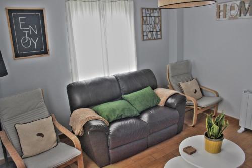 a living room with a leather couch and two chairs at River Home Ponteceso Camiño dos Faros in Ponteceso