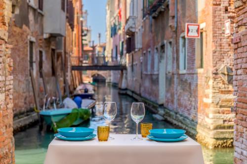 a table with two wine glasses and a view of a canal at Ramo del teatro Canal view in Venice