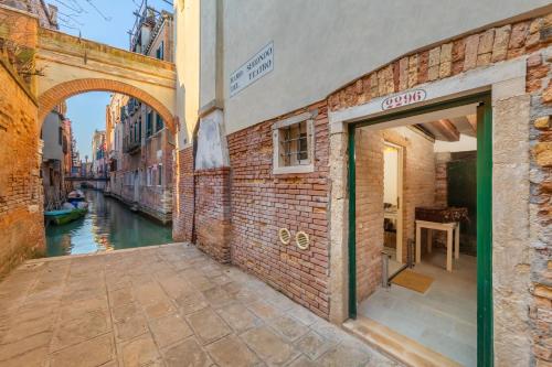 ヴェネツィアにあるRamo del teatro Canal viewの運河の隣に開いたドアのあるレンガ造りの建物
