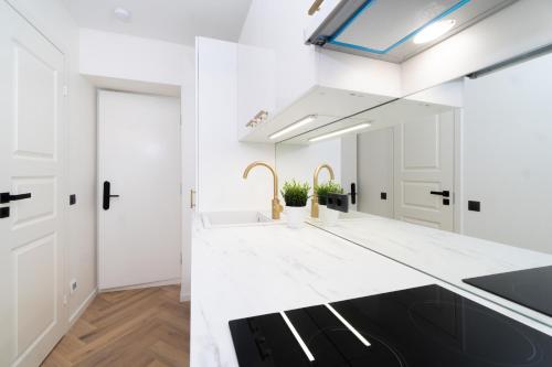 - une cuisine blanche avec un évier et un miroir dans l'établissement Tallinn Airport Studios by Revalhome, à Tallinn
