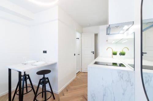 a white kitchen with a counter and a stool at Tallinn Airport Studios by Revalhome in Tallinn