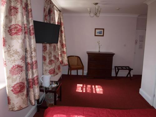 ブリクサムにあるManor Inn Galmptonのベッド、テレビ、カーテンが備わる客室です。