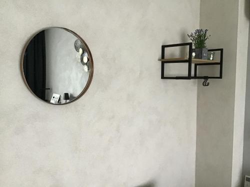 a round mirror on a wall with a shelf at Guesthouse De Steenberg tweepersoonskamer met grote badkamer, kitchenette en tuinzicht op de eerste verdieping in Geel