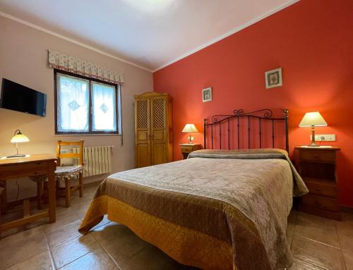 CoraoにあるSantu Colásの赤い壁のベッドルーム1室、ベッド1台、デスクが備わります。