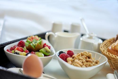 a tray with three bowls of fruit and an egg at Parkhotel Gütersloh in Gütersloh