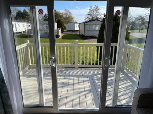 an open door to a porch with a white fence at private rented caravan situated at Southview holiday park in Winthorpe