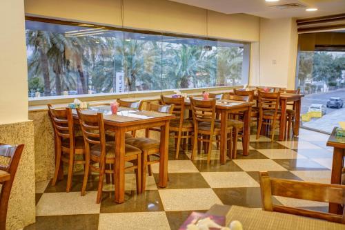 a restaurant with wooden tables and chairs and a large window at Nairoukh Hotel Aqaba in Aqaba