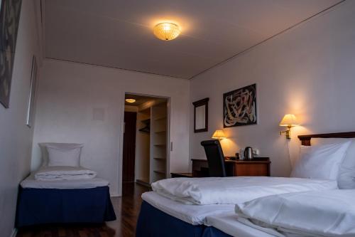 a hotel room with two beds and a desk at Hotel Phønix Hjørring in Hjørring