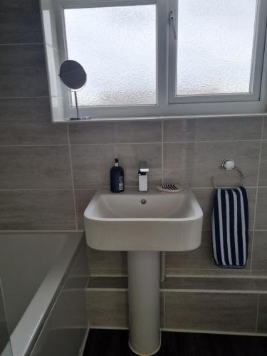 a white sink in a bathroom under a window at Anniversary Cottage- Country feel, close to Cromer in Northrepps