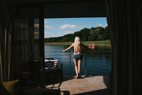 Eine Frau, die auf einem Dock in der Nähe des Wassers steht. in der Unterkunft Domek na wodzie Topiko Czarter - jezioro Mamry in Angerburg