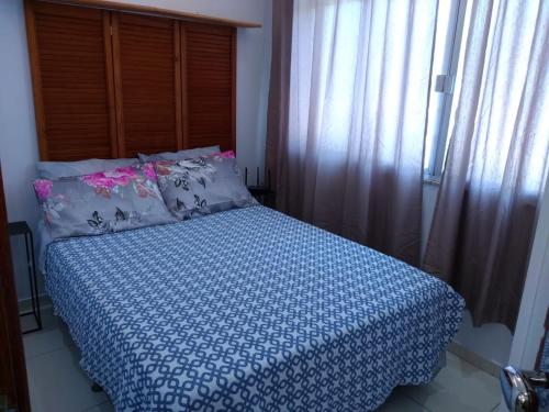 a bedroom with a bed with a blue and white comforter at Loft Aconchegante no Centro de Niterói! in Niterói
