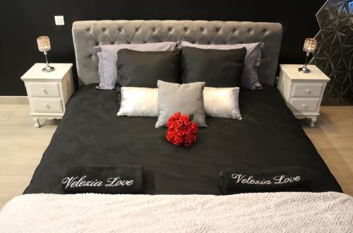 a bed with a black blanket and a red flower on it at Velezia LOVE in Roujan