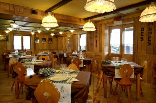 ピーラにあるHotel Chalet des Alpesの木製のテーブルと椅子、シャンデリアが備わるレストラン