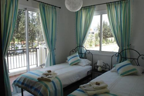 een slaapkamer met 2 bedden en een groot raam bij The well-equipped luxury apartment Paphos Riviera in Paphos City
