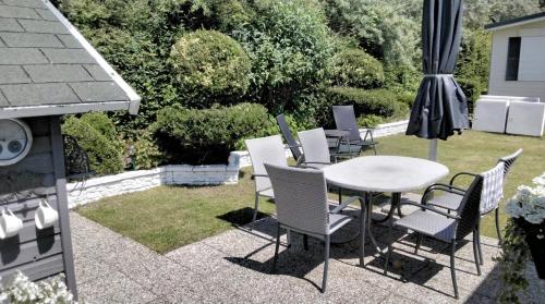 a patio with a table and chairs and an umbrella at Zandput 490 - Camping de Zandput in Vrouwenpolder