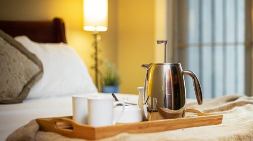 a tray with a coffee pot and cups on a bed at Solara Resort by Bellstar Hotels in Canmore