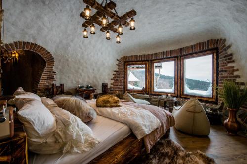 een slaapkamer met een groot bed in een kamer met ramen bij Osada Jaworzyny - Domek Hobbita z jaskinią SPA in Tokarnia