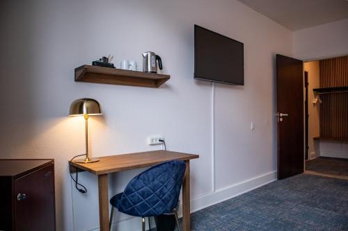 a hotel room with a desk and a tv on the wall at Hotel Phønix Hjørring in Hjørring