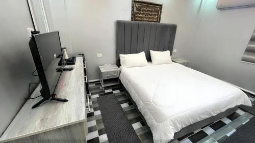 a small bedroom with a bed and a television at Petra Pillars Way Hostel in Wadi Musa