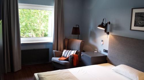 une chambre d'hôtel avec un lit, une chaise et une fenêtre dans l'établissement Hotel Henry, à Dreieich