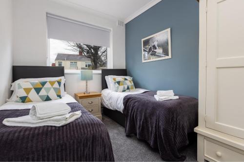 2 camas en una habitación con paredes azules y ventana en Hillside House - 2 Bedrooms parking WI-FI Hospital en Blackpool