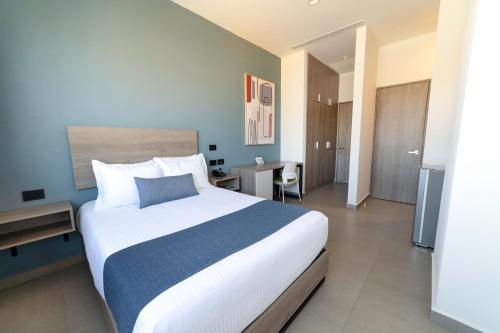 a bedroom with a large white bed and a desk at TH HOTEL & VIVIENDA in Tepatitlán de Morelos