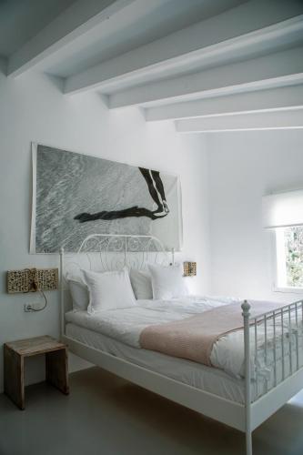 a bedroom with a white bed with a painting on the wall at Ecocirer Guest House in Sóller