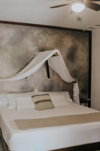 a bedroom with a white bed with a painting on the wall at Casa de Olas Boutique Hotel in Puerto Escondido