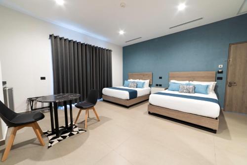 a bedroom with two beds and a table and chairs at TH HOTEL & VIVIENDA in Tepatitlán de Morelos