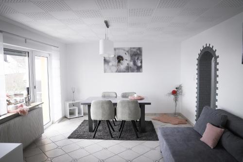 a white living room with a table and chairs at Ferienwohnung Panoramablick-Rhön in Sandberg