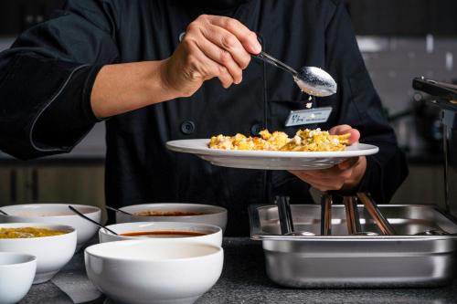 a person holding a plate of food with a spoon at TH HOTEL & VIVIENDA in Tepatitlán de Morelos