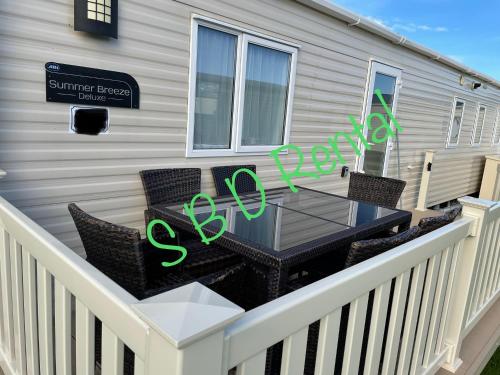 Saint Osyth的住宿－Summer Breeze Deluxe Caravan Rental，阳台的天井配有桌椅