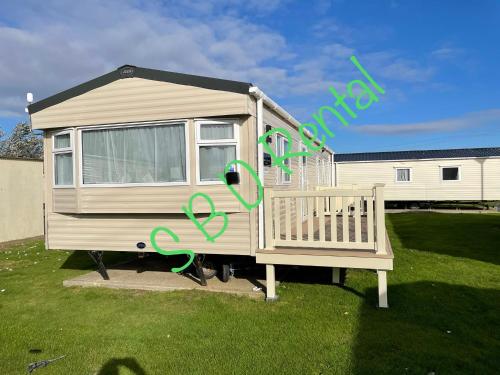 una casa móvil con algo de escritura verde en ella en Summer Breeze Deluxe Caravan Rental en Saint Osyth