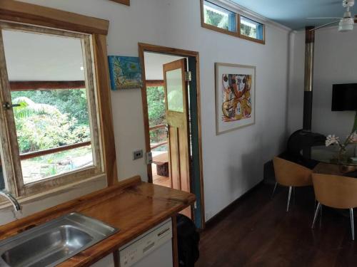 a kitchen with a sink and a window and a table at Sweetwater Cottage. A private mountain escape in Upper Burringbar