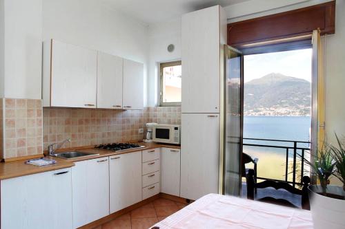 a kitchen with white cabinets and a view of the ocean at Miralago Casa in Menaggio