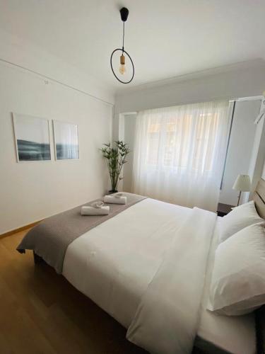 Un dormitorio con una gran cama blanca y una ventana en Lovely apartment in the heart of Athens, en Atenas