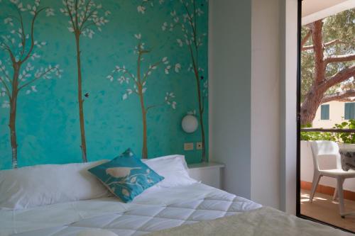 a bedroom with a bed with a blue wall at Hotel Punto Verde in Marina di Campo