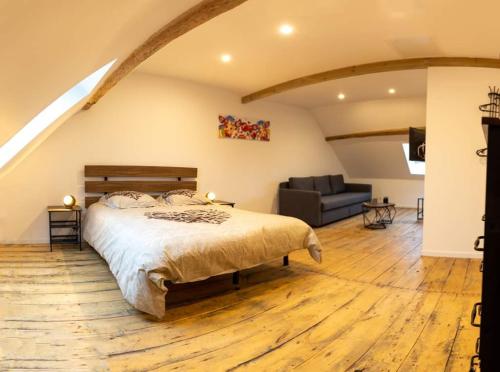 a bedroom with a bed and a couch at CYRIS - Chambres Duplex climatisées - Spa & Piscine Centre ville in Saint-Germain-des-Fossés