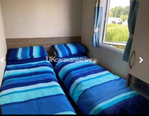 two beds in a small room with a window at Caravan Primrose Valley WW in Hunmanby