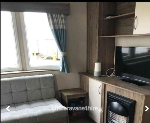 a living room with a couch and a television at Caravan Primrose Valley WW in Hunmanby