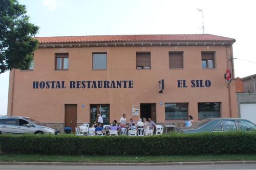a group of people sitting at tables in front of a building at Hostal Restaurante El Silo in Santa María del Páramo