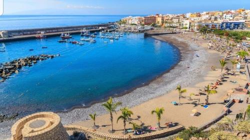 a beach with a group of people and boats in the water at Apartamentos Jose in Playa de San Juan