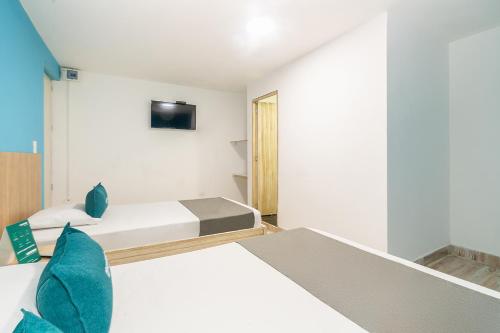 a bedroom with two beds and a tv on the wall at Ayenda Malaki in Medellín