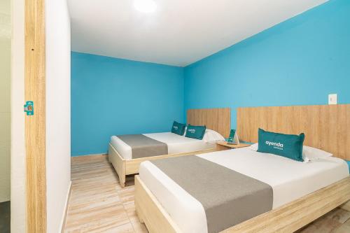 a bedroom with two beds and a blue wall at Ayenda Malaki in Medellín