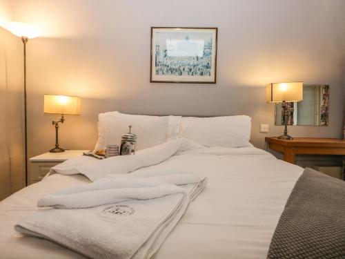 ein weißes Bett mit Handtüchern darauf in der Unterkunft Eller Riggs Cottage in Ulverston